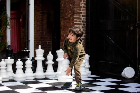 Boy playing with giant chess set outside Bruce Castle Museum