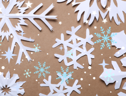 Cut out paper snowflakes on light brown background