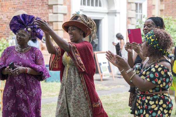 people smiling and clapping at a windrush day celebration at bruce castle