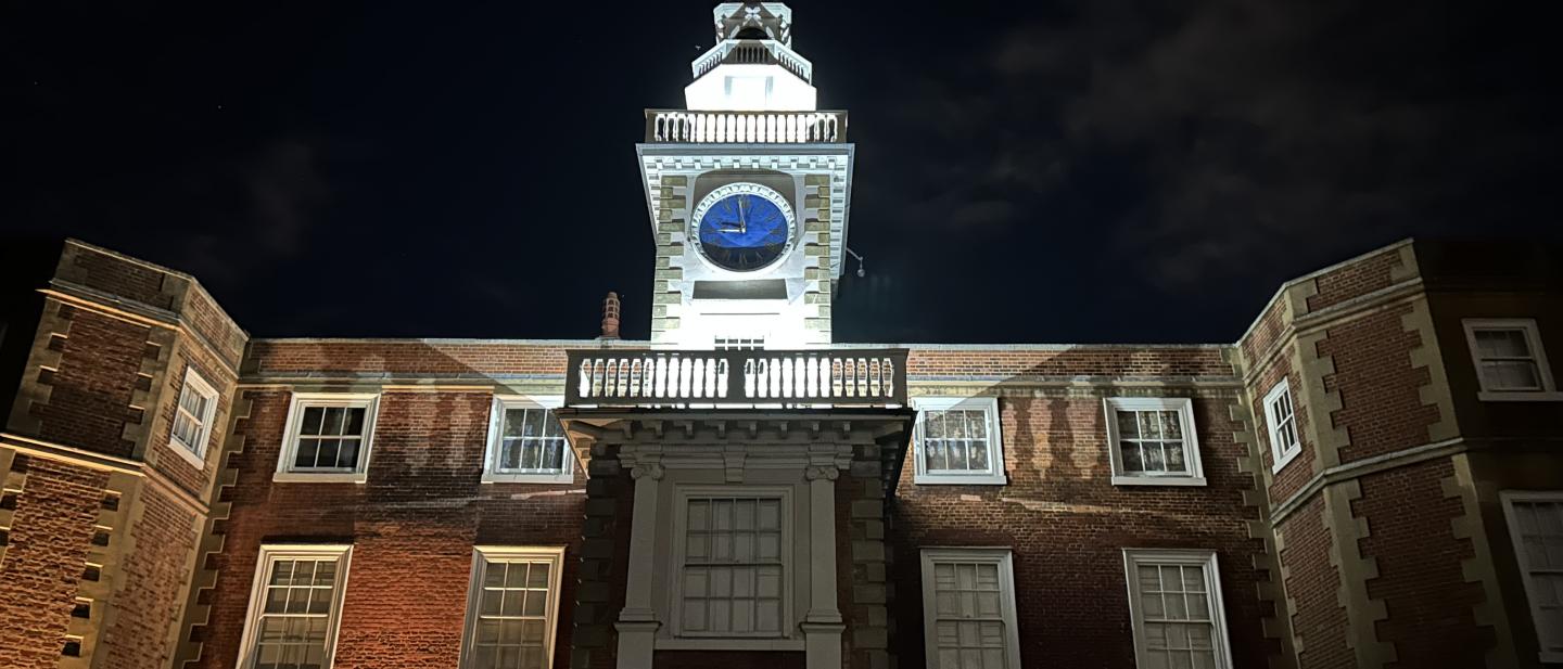 Manor house clocktower lit up in the dark