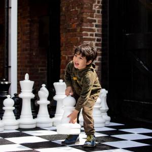 Boy playing with giant chess set outside Bruce Castle Museum