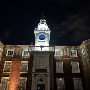 Manor house clocktower lit up in the dark